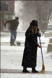 It's push against shove as Jennifer Simpson, foreground, an
employee at Prairie Pond Studio, 809 Mass., uses a broom to sweep
snow from her sidewalk. Wednesday's snow accumulation totaled 1
inch, but a high of only 19 degrees made the day the coldest so far
this season. The National Weather Service put out a wind chill
advisory for Wednesday night in the area, predicting temperatures
of 5 degrees below zero with a wind chill of minus 25 degrees. See
today's forecast on page 8B.