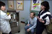 Registered nurse Jenny Takeda, left, talks to patient Richard
Snyder and his wife, Debbie, at St. Joseph Hospital in Orange,
Calif., about using a home dialysis machine.