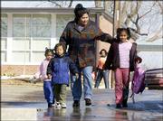 After meeting her daughter Senia, 6, right, a student at East
Heights School, Fika Stanford and her other children, Sina, 2, and
Charles, 3, walk back to their house in East Lawrence. Under the
proposed school bond, students at East Heights would move into an
expanded New York School, and the East Heights building would
become an early childhood education center.