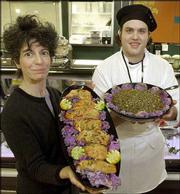 Sula Teller, left, is the new food service manager at Community
Mercantile Co-op, 901 Iowa. Teller displays a platter of
saki-marinated roasted salmon in a sweet soy glaze. Tim Quillin,
chef de cuisine, shows a bowl of lentil salad with onions, bell
pepper and olive oil.