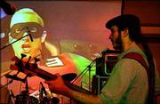 Willy Rodriguez, lead singer and bass player for Cultural
Profetica, warms up in front of a video display showing rap star
Eminem. Youths across Latin America and the Caribbean are turning
their backs on traditional salsa, mesmerized by music videos and
seeking to carve out a musical niche that's in step with their
generation.