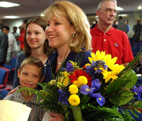 The Self family, clockwise from upper left, Lauren, 12, Cindy
(holding flowers) and Tyler, 9, greet passersby after a news
conference in which Bill Self was appointed the new KU men's
basketball coach.
