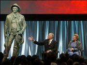 Outgoing National Rifle Assn. president Charlton Heston gestures
toward a statue of the character he played in the movie "Will
Penny" with his wife, Lydia, at his side in Orlando, Fla. The
statue was presented to Heston on Friday at an NRA tribute in his
honor; Saturday, he made he last appearance as NRA president.