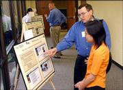 Robert Isaacson, left, and Thanawan Phongsatha, both with the
Center for Research on Learning at Kansas University, talk about
one of the posters during KU's Information and Telecommunication
Technology Center's Technology Day. During the Technology Day
celebration Monday, Sprint Corp. and KU announced that their
10-year partnership had produced a third patented discovery.