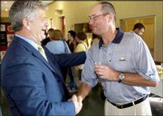 Dick Patterson, left, receives kind regards from Dick Stuntz,
Lawrence, during a farewell reception in his honor at the Lawrence
Visitor's Center. Patterson, a Topeka resident who became principal
of Lawrence High School in 1997, plans to take a job as principal
of the Auburn-Washburn school district alternative high school
program.