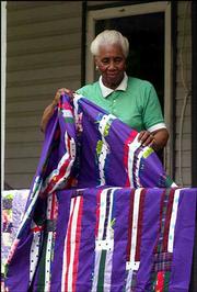 Arlonzia Pettway folds one her many quilts on the porch of her
Gee's Bend, Ala., home. Pettway quilts with a group of local black
women who recently gained international recognition for their quilt
exhibition at the Whitney Museum in New York.