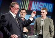 Nextel CEO Tim Donahue, left, holds a phone painted to resemble the
NASCAR vehicle of Jeff Gordon, center, as Dale Earnhardt Jr. looks
on. NASCAR got a new title sponsor for its top stock car racing
series beginning in 2004, signing a 10-year deal with Nextel
Thursday in New York.
