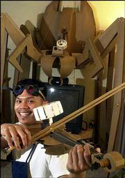 Artist Juniper Tangpuz loves to integrate art and life --
especially in his personal living space. Tangpuz, a recent Kansas
University graduate from Kansas City, Mo., is shown playing his
handmade zoetrope (moving picture device) in his living room while
a sculpture called "Fiddle Back" looms above his television. Both
sculptures are made from paper materials.
