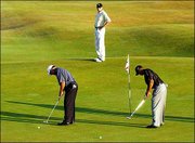 A security official, center, watches as Mark O'Meara, left, and
Tiger Woods putt during a practice round for the British Open golf
championship at Royal St. George's golf course. The two practiced
Tuesday in Sandwich, England.