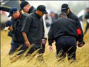 Golfer Tiger Woods, center, searches for his ball in the rough with
course officials at Royal St. George's during the first round of
the British Open. Woods shot 2-over 73 Thursday in Sandwich,
England.