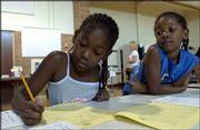Imani White, 8, left, fills out a form to enroll in the Boys and
Girls Club of Lawrence after-school program with her sister Tiani,
6, right. The sisters were going through enrollment Wednesday at
Pinckney School with their mother, Ambe Dowdell-White, Lawrence.
Both girls attended Riverside School last year.