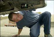 John LaSage demonstrates how to set a surveillance vehicle tracker
underneath his truck's bumper. LaSage, a Southern Californian,
established the Chatcheaters Web site after his wife left him to
join a man she met online. Chatcheaters offers advice, surveillance
equipment and first-person stories of betrayal. The vehicle tracker
keeps a computer-readable log with exact time and locations, with
the help of a satellite GPS receiver.