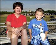 Sarah Narcomey, left, and her son, Justin, 7, both of Lawrence,
await the beginning of the demolition derby at the Douglas County
4-H Fairgrounds. The event was Aug. 1.