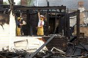 Tonganoxie firefighters, from left, Curtis Newman and Ronnie
Stovich, clean up some of the damage at an early morning fire at
303 East Third St., where a house was totally destroyed by fire.