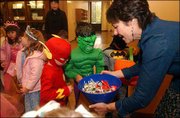 From left, 5-year-olds Griffin Nelson, Sammy Rosenstengle, and
Braden Smith look over the candy selection offered by Robin Miller,
an administrative specialist at the Kansas University law school.
Students from Hilltop Child Development Center paraded their
Halloween costumes Friday morning at KU and picked up some treats
along the way.