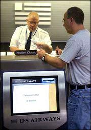 Jim Smyers, of Glen Allen, Va., gets his paperwork checked by a US
Airways ticket agent, who declined to be identified, at Richmond
International Airport in Richmond, Va. Smyers checked in using the
automated kiosk, lower left, but had to go for human help when the
machine's printer ran out of paper.