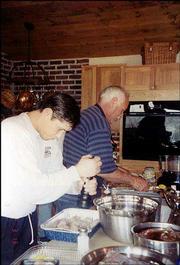 Michael Deutsch, left, son of Mel Deutsch, helps Dave Billings
prepare for a "wild game feed." Billings and his friend, Mel
Deutsch, play host to an annual party for family and friends. The
dishes they prepare feature the game they caught while hunting.
This picture was taken at a party two years ago at Billings&squot; rural
Lawrence home.