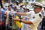 Ensign Mary Alcantara, 23, from Northridge, Calif., center, and Lt.
j.g. Don Shrader, 31, right, from San Diego, shop for souvenirs in
Ho Chi Minh City, formerly Saigon, Vietnam. The two naval officers
are from the USS Vandegrift, which on Wednesday became the first
US. Navy ship to dock in Ho Chi Minh City since the end of the
Vietnam War.