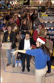 The lines were long at Best Buy as customers arrived early to scoop
up special deals. Employee Becca Hinckley, bottom right, helped
direct holiday shoppers to checkout lanes Friday at the store at
31st and Iowa streets. Lawrence shoppers joined millions of others
nationwide for one of the busiest shopping days of the year.