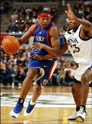 Kansas University freshman J.R. Giddens, left, drives on Garry
Hill-Thomas in the first half. The Jayhawks fell to the Wolf Pack,
75-61, late Sunday night in Reno, Nev.