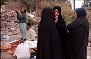 Iranian men pray as women stand next to their destroyed house in
Bam, Iran. The provisional death toll in Iran's earthquake is
20,000 with more than 30,000 people injured, the Interior Ministry
said.