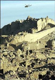 A helicopter flies over the damaged fortress of Bam, some of which
dates back 2,000 years. Most of the ancient citadel was destroyed
by Friday's earthquake. One American was killed and another injured
as they visited the historic site. "My grief is twofold," said Reza
Husseini, a 25-year-old archaeology student. "I've lost two members
of my family, and I've lost my history, my citadel."