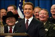 California Gov. Arnold Schwarzenegger is joined by law enforcement
and government officials during a news conference on the state
budget at the Capitol in Sacramento. Schwarzenegger's successful
venture into politics was just one of the instances where celebrity
and reality collided in 2003.
