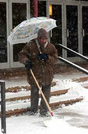 Subramania Natrajan, a Kansas University employee who works at
Murphy Hall, used an umbrella Thursday morning to ward off heavy
snow as he shoveled the sidewalk.