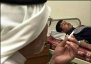 An Iraqi policeman lies in a hospital bed in Fallujah, Iraq, after
being wounded when guerrillas launched an assault on an Iraqi
police station and security compound. The gunbattle killed 23
people.