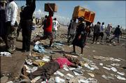 Looters walk past a dead man in Port-au-Prince. The man was killed
during looting that erupted Friday morning in the Haitian capital.
Rebels pushed to within 25 miles of the capital Friday as chaos
spread with government loyalists torching barricades, hijacking
cars and looting