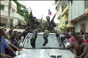 Rebel leader Louis-Jodel Chamblain sits atop a car, at right, after
news of Haitian President Jean-Bertrand Aristide's departure
reached northern Cap-Haitien.