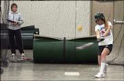 Free State High senior Felicia Freeman hits during the first day of
softball practice as coach Pam Pine looks on at left. Because of
soggy field conditions, softball and baseball practices were moved
inside Monday, the first day of practice for high school spring
sports.