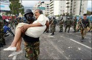 A Venezuelan National Guard soldier helps an elderly woman escape
from tear gas and rubber bullets during brief clashes with
anti-President Hugo Chavez protesters in Caracas, Venezuela. A
recall effort against Chavez was denied Tuesday as election council
members said not enough petition signatures were confirmed.