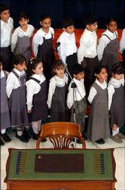 School children practice singing the Iraqi National Anthem behind a
table with 25 pens and an empty chair lying idle in the middle of
the lobby of the Convention Center for the historic new Iraqi
interim Constitution in Baghdad, Iraq. The signing ceremony by the
25-member Iraqi Governing Council was delayed for more than five
hours and then canceled after Shiite leaders refused to sign the
interim constitution. Iraq's top Shiite cleric had rejected
portions of the charter.