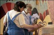 Debbie Snyder, Topeka, and Anna Sylvester, Lawrence, look over
items for sale at the East Lawrence Neighborhood Assn. Yart Sale.
The event was March 27 at New York School.