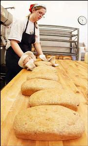 Baker Bri Hickman, Lawrence, transfers low-carbohydrate bread to
the cooling racks at Great Harvest Bread Co., 807 Vt. The Atkins
diet craze has affected many businesses like Great Harvest, which
sells high-carb items such as breads and cookies. Subsequently, the
bakery has introduced a bread with most of the wheat flour taken
out, which reduces the amount of carbs.