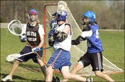Kansas University junior Nate Macon, center, attacks the goal with
freshman Matt Elder playing defense and sophomore Kent Domas as
goalie. Defenders try to knock the ball out of the player's stick
by checking with their own stick. The three play for the KU Men's
Lacrosse Club.
