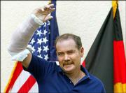 U.S. civilian contractor Thomas Hamill, from Macon, Miss., waves
with his injured arm to the media from a balcony at the Regional
Medical Center in Landstuhl, western Germany. Hamill is being
treated in Landstuhl after escaping his Iraqi captors on Sunday.
His wife, Kellie, is expected today in Germany for a reunion.