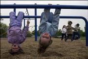 Moira Modrzynski, 6, left, and Kearston Mohney, 6, hang upside down
on monkey bars at Kennedy School, 1605 Davis Road. The Lawrence
children attended Kennedy's after-school program on Friday. Three
Lawrence schools, including Kennedy, face the potential of seeing
the federal grant money for their after-school programs run out
this year.