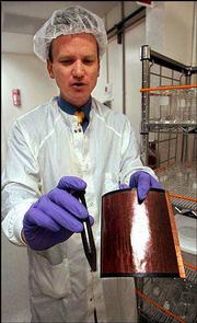 Martin Roscheisen, CEO of Nanosolar Inc., holds up a vial of the
company's secret formula for making the solar panel at right. He
was photographed April 2 in the company's lab in Palo Alto, Calif.
Nanosolar is developing a new generation of solar energy cells
which has attracted investors.