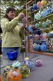 Julie Bortner-Scharf, Lawrence, looks over decorative ornaments at
Art in the Park. The 43rd annual event, sponsored by the Lawrence
Art Guild, was Sunday in South Park.