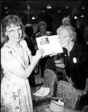 Beth Ankerholz, left, Bert Nash Community Mental Health Center
information technology director, and Lauraine Mulally, Lawrence,
look at a copy of the center's history. A 1940 photo of Mulally and
Dr. Bert Nash appears on the page at left. The women attended the
center's 18th annual Pioneer Celebration on April 20.