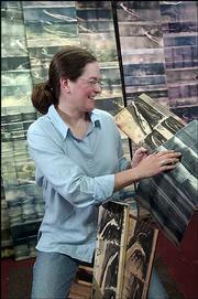 "Prairie River," an exhibition by Lawrence artist Lisa Grossman,
opens Tuesday at the Lawrence Arts Center, 940 N.H. The show
features paintings and prints of aerial views of the Kansas River
that Grossman photographed from an airplane. In her studio Tuesday,
Grossman explained how she used wood cuts to relief roll images
onto tissue paper that she mounted on mulberry paper and fixed to
panels to form "86 Bends of the Kaw," shown behind her.