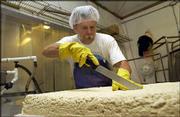 Jeff Sexton, production manager at Central Soyfoods, cuts a
60-pound block of tofu into smaller pieces for hickory smoking. The
Lawrence company, which produces a number of soy products, has
reported an increase in sales. Sexton was pictured last week at the
company.