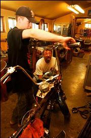Casey Pollard, 16, of Lecompton, a mechanic at Hog Works, gets help
from owner Randy Lester. The reality-television show "American
Chopper" has provided a boost in business for the motorcycle
industry.