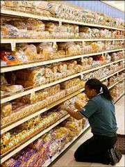 Shancell Ward, of Washington, D.C., stacks white bread on shelves
at a grocery store in Washington. Scientists say white bread and
other refined grains seem to go to the gut and hang out as belly
fat.