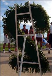 Kennith Bateson, Father of Krystal Bateson, looks at flower
arrangement shaped in a number two, the number Krystal wore while
playing for the Phenix softball team.
