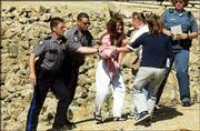 Lawrence Police officers help an emotional member of Lathrom's
family up the levee on the Kansas River in North Lawrence.