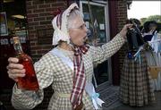 Christine Reinhard, of Lawrence, finds "illicit spirits" at the
Round Corner Drug Store during the Temperance Rally from the
Watkins Community Museum of History to the Free State Brewing Co.
Men and women dressed in period clothing marched Friday down
Massachusetts Street, pouring out the spirits they found at local
"groggeries" along the way.
