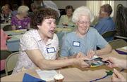 Gloria Bagby, left, and Darlene Lovelett look at some pictures
before a salad luncheon given by the Lawrence Central United
Methodist Women. The group invited other United Methodist Women
groups on June 16 to share stories about the women's mission work
at their churches.
